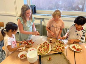 Die Brotscheiben werden von 4 Kindern mit den Tomatenwürfeln belegt