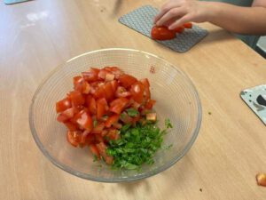 Man sieht eine Schüssel mit Tomatenwürfeln und gehackten Kräutern