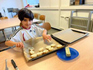 Die Brotscheiben werden von einem Jungen mit Kräuterbutter bestrichen.