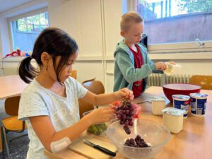 Kinder bereiten Quarkspeise und Obstsalat zu.